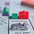 close up of a Monopoly board with a car on Boardwalk and houses and hotels around