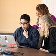 Three women entrepreneurs sitting at the table looking at laptop