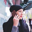 woman in a black toque holding cell phone to her ear, looking concerned