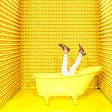 Man comically drowning in yellow bathtub surrounded by walls of rubber duckies.