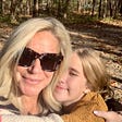 Blonde woman with sunglasses smiling and hugging adolescent daughter on a hike.