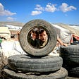 Boys looking through a abandoned wheel well in a refugee camp.