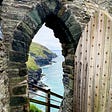 Seaside cliffs visible through an old stone arch