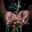 Water pouring into a person’s cupped hands.