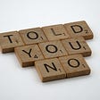 Scrabble letters that spell out “told you no” on white background.