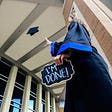 Graduate throwing hat into the air and holding a sign that says “I’m done!”