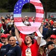 A man holds up a “Q” sign while waiting in line to see President Donald Trump at his rally on August 2, 2018 in Wilkes Barre, Pennsylvania.
