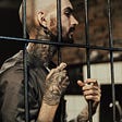 tattooed man behind bars.