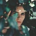Young woman peering through the leaves of a tree