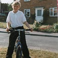A young Joel as a child in his school uniform on his bicycle smiling for the camera on a summers day