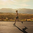 A shirtless man running on the road in the sun