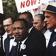 This is a picture of Dr. Matin Luther King and he is surrounded by people who are dressed in suits who are holding signs.