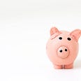 A pink piggy bank with small black eyes and nostril stands right of center on a white gradient background.