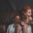 A redheaded young woman is laughing.