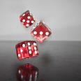 Three red dice bouncing of a black table
