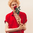 Picture of a skinny guy smelling a rose.