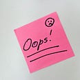 “Oops” and sad face on a pink PostIt note