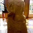from behind a seated couple sculpted  in marble, entwined.their profiles kiss as sunlight filters through the spaces between.