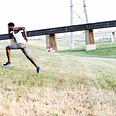 man sprinting up a grassy hill in athletic gear