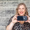 A happy and confident woman with a double chin getting ready to take a photo of herself with her camera