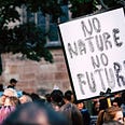 Climate Change protestor holding sign that says “NO NATURE NO FUTURE” among crowd of other protestors.