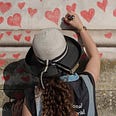 a girl drawing hearts on a wall