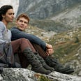 Rand and Egwene from The Wheel of Time TV show sitting together on a hillside.