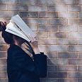 Girl holding a book over face. Picture from https://unsplash.com/@siora18