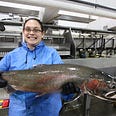 AmeriCorps member Kylee shows off a smile and a huge salmon