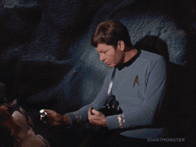 Dr. McCoy inspects an alien with a tricorder.