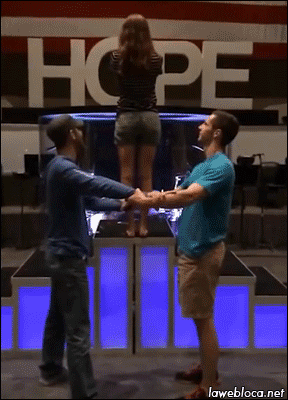 Woman falls backwards, falls through the arms of the two men waiting to catch her