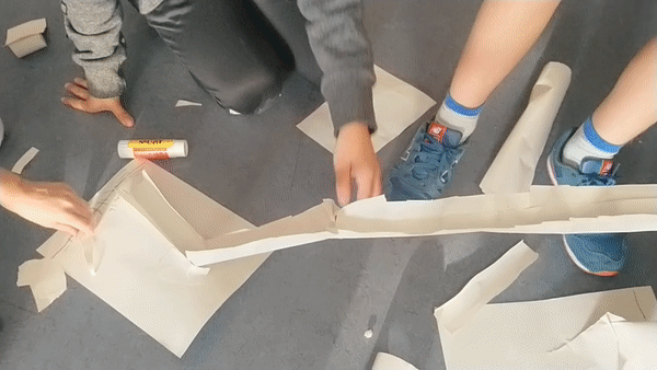 kids dropping a paper ball down a paper slide