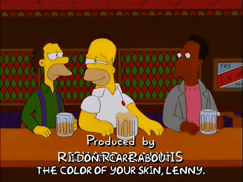 Homer Simpson sits at a bar between two colleagues. He tells his white colleague, “I don’t care about the color of your skin, Lenny,” while his Black colleague looks on.