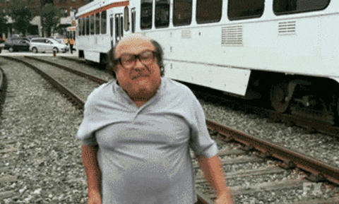Danny Devito at a train station angrily giving the middle finger