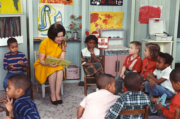 First Lady Lady Bird Johnson visits a Head Start class in 1966. By White House Photograph Office, Robert L. Knudsen. — This media is available in the holdings of the National Archives and Records Administration, cataloged under the National Archives Identifier (NAID) 596401., Public Domain, https://commons.wikimedia.org/w/index.php?curid=4192751