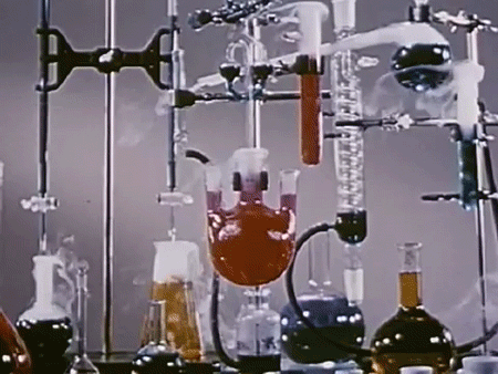 Steam rises from various flasks and volumetric tools attached together with metal clamps and filled with different-colored liquid.