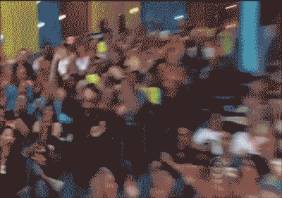 Man runs through cheering audience to front seats and jumps excitedly