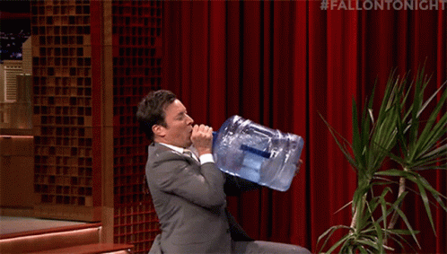 Jimmy Fallon falls over as he attempts to drink out of a 5-gallon water cooler jug.