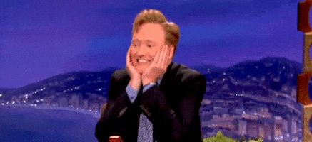Conan O’Brien cupping his chin happy dancing gif