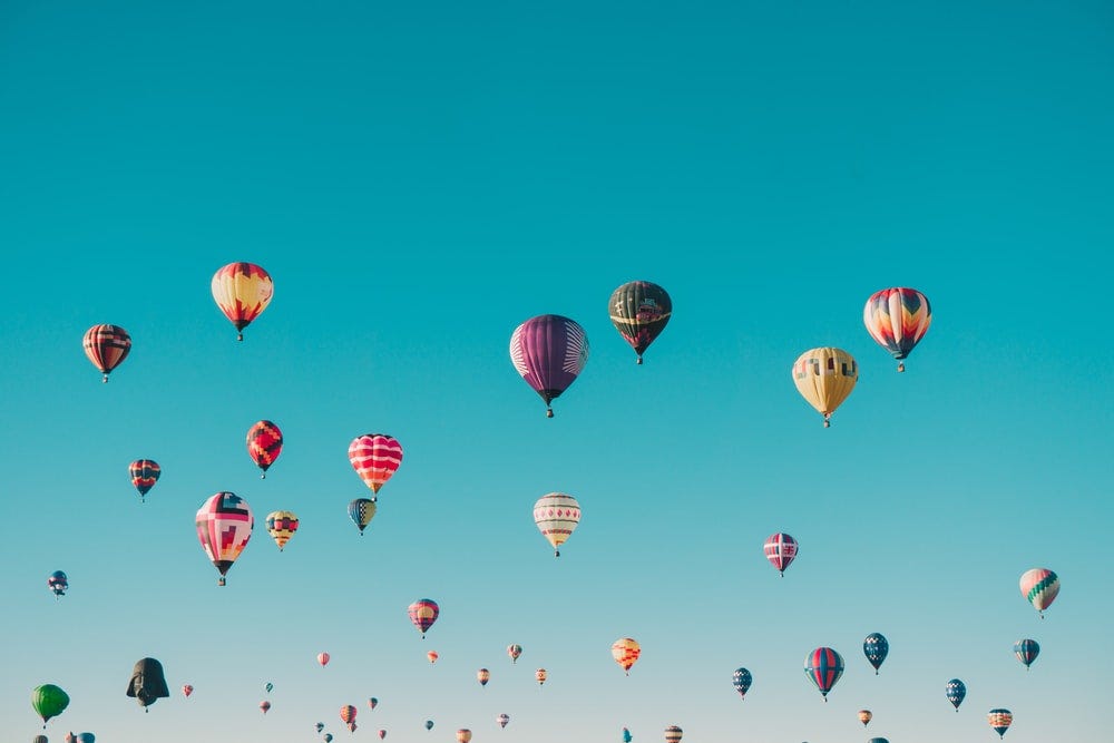 Many, many hot air balloons against a blue, blue sky.