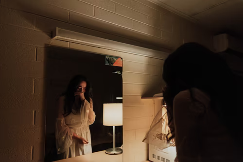 A woman crying in front of a mirror.
