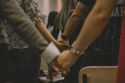 A group of people holding hands in prayer
