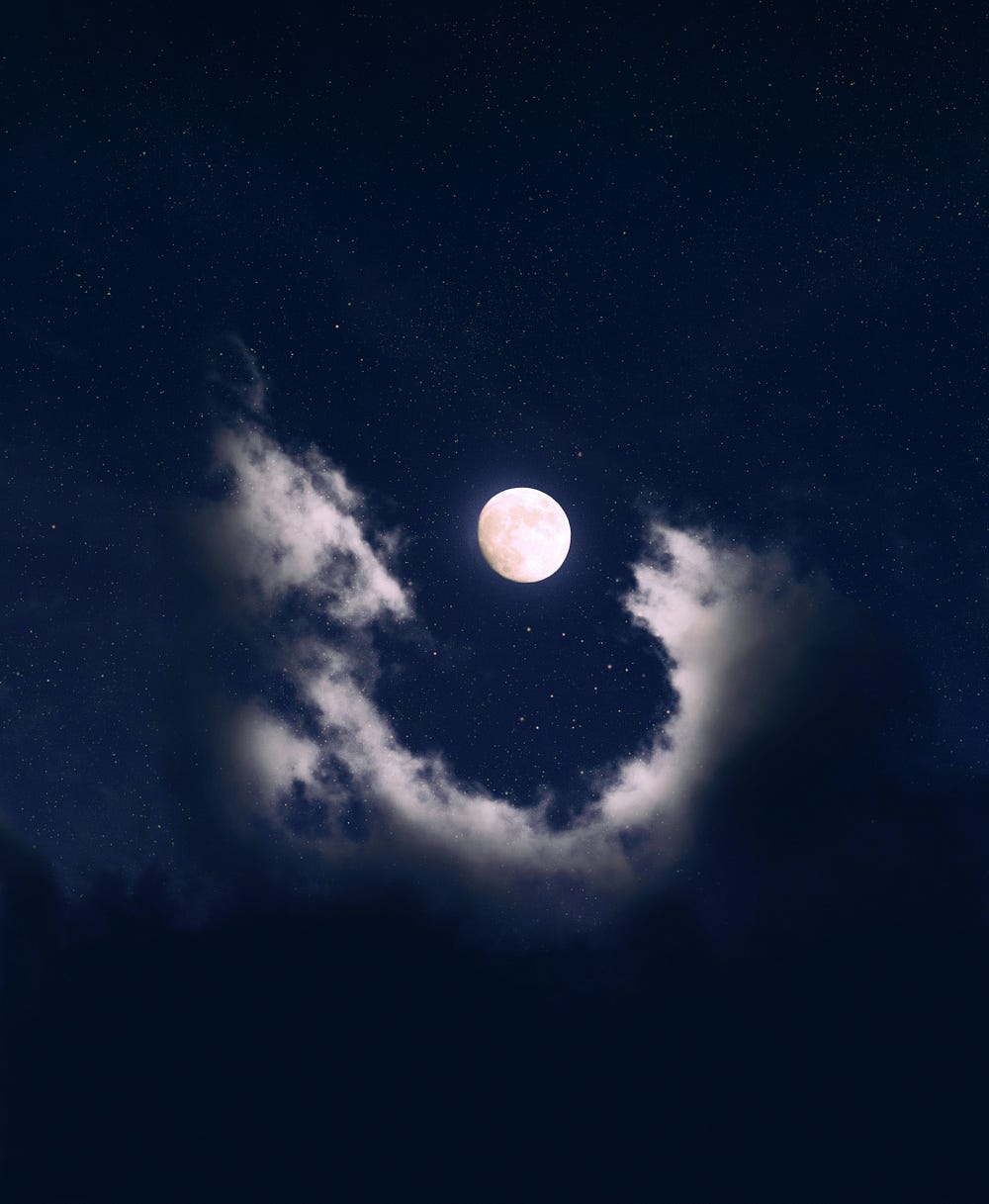 A nearly full moon glows lavender in the middle of a cloud that makes a U-shape underneath it.