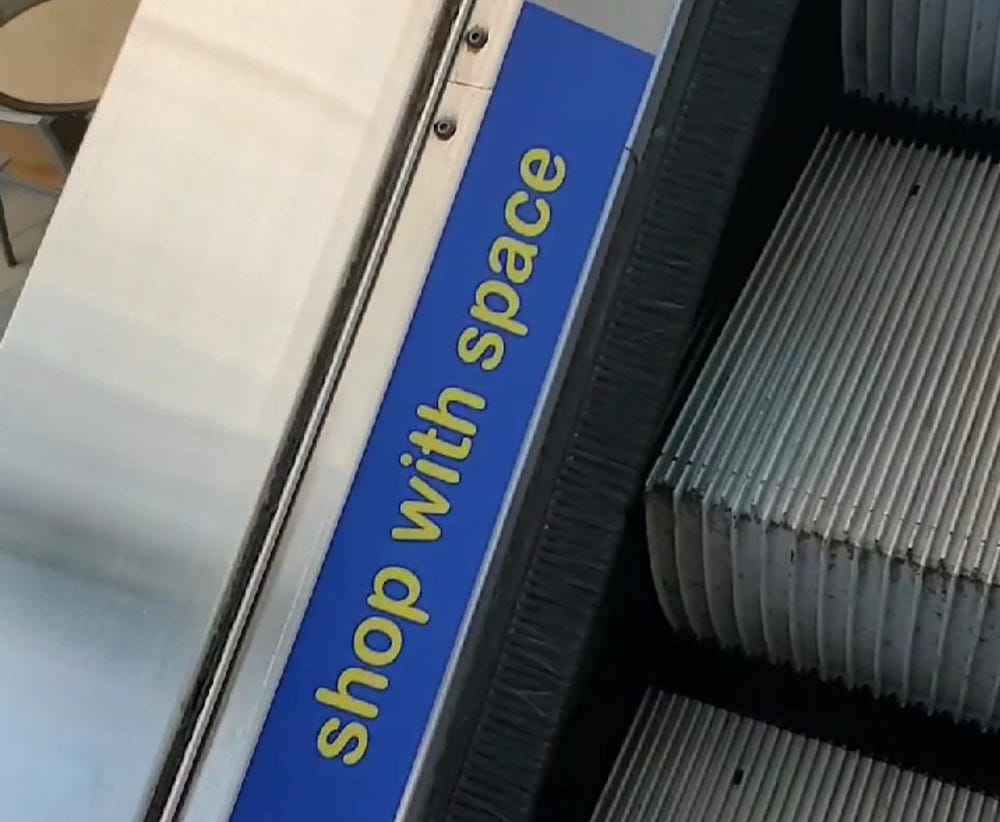 A photo of a sticker that reads “shop with space” that lined the escalator in the mall.