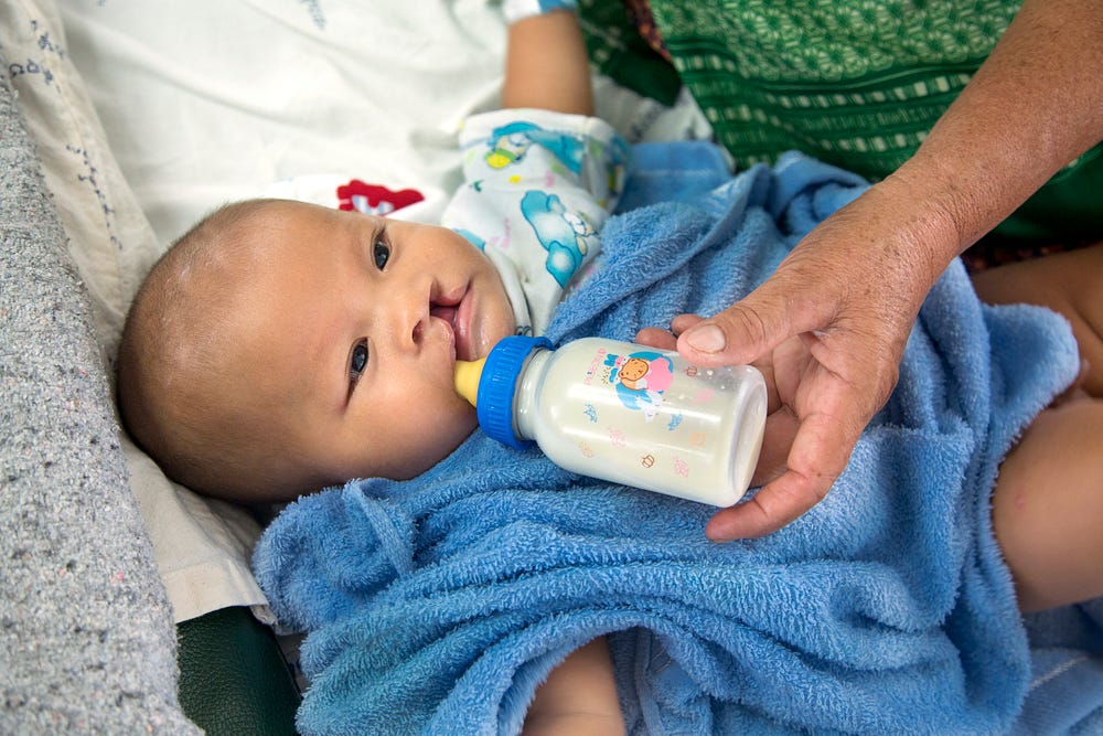 Pitchaya, a little boy from Thailand sucks on a bottle from his grandmother.
