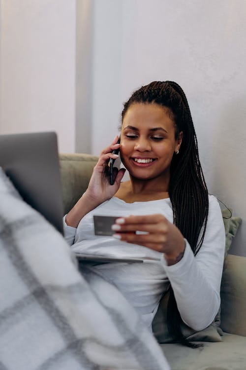 Picture of a woman on the phone holding a credit card in her hand.
