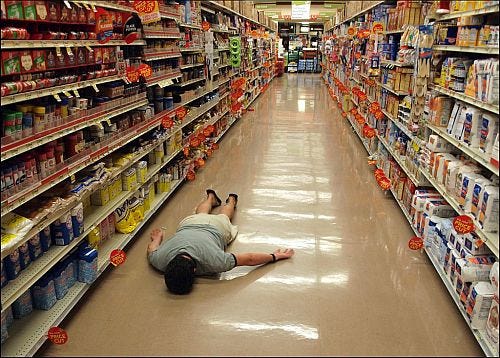 Person lying face down in a grocery store aisle. Indicative of how I feel out of place where I currently find myself in life.