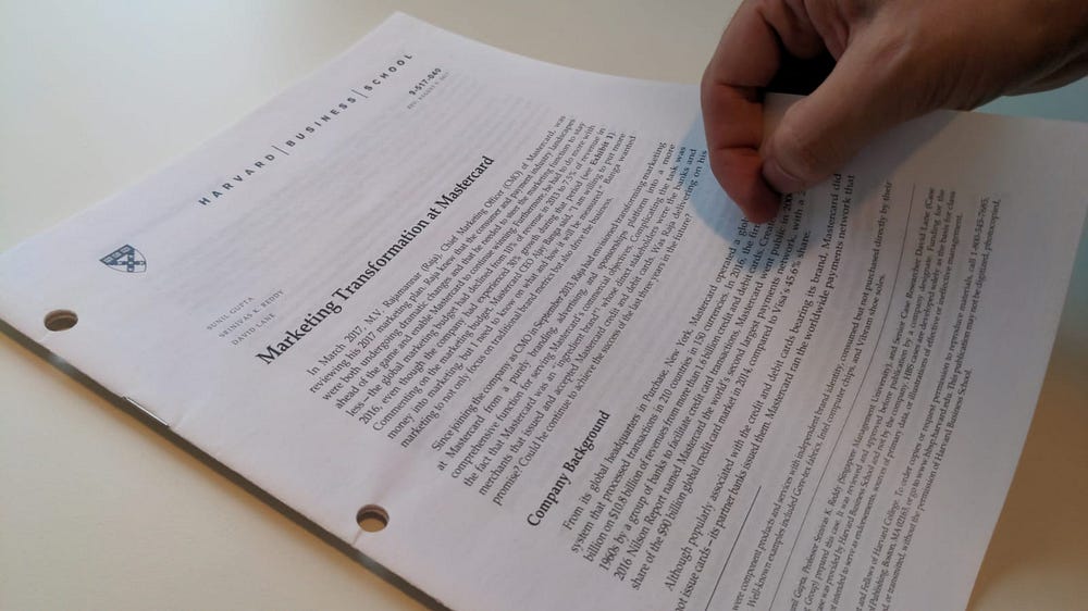 A Harvard Business School case study with a hand turning the front page