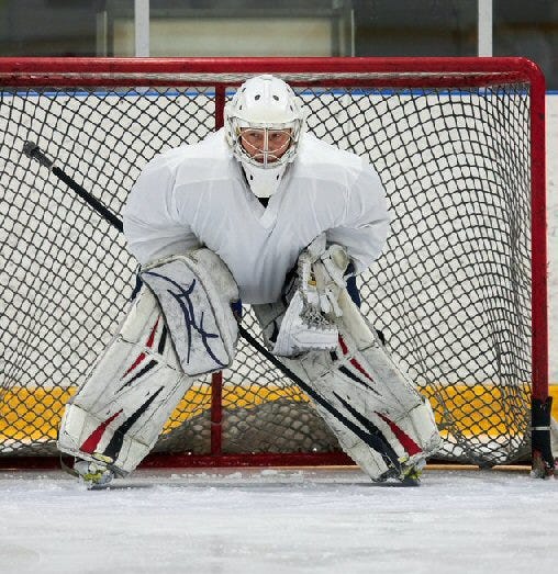 A photo of a hockey goaltender standing in front of ais goal.