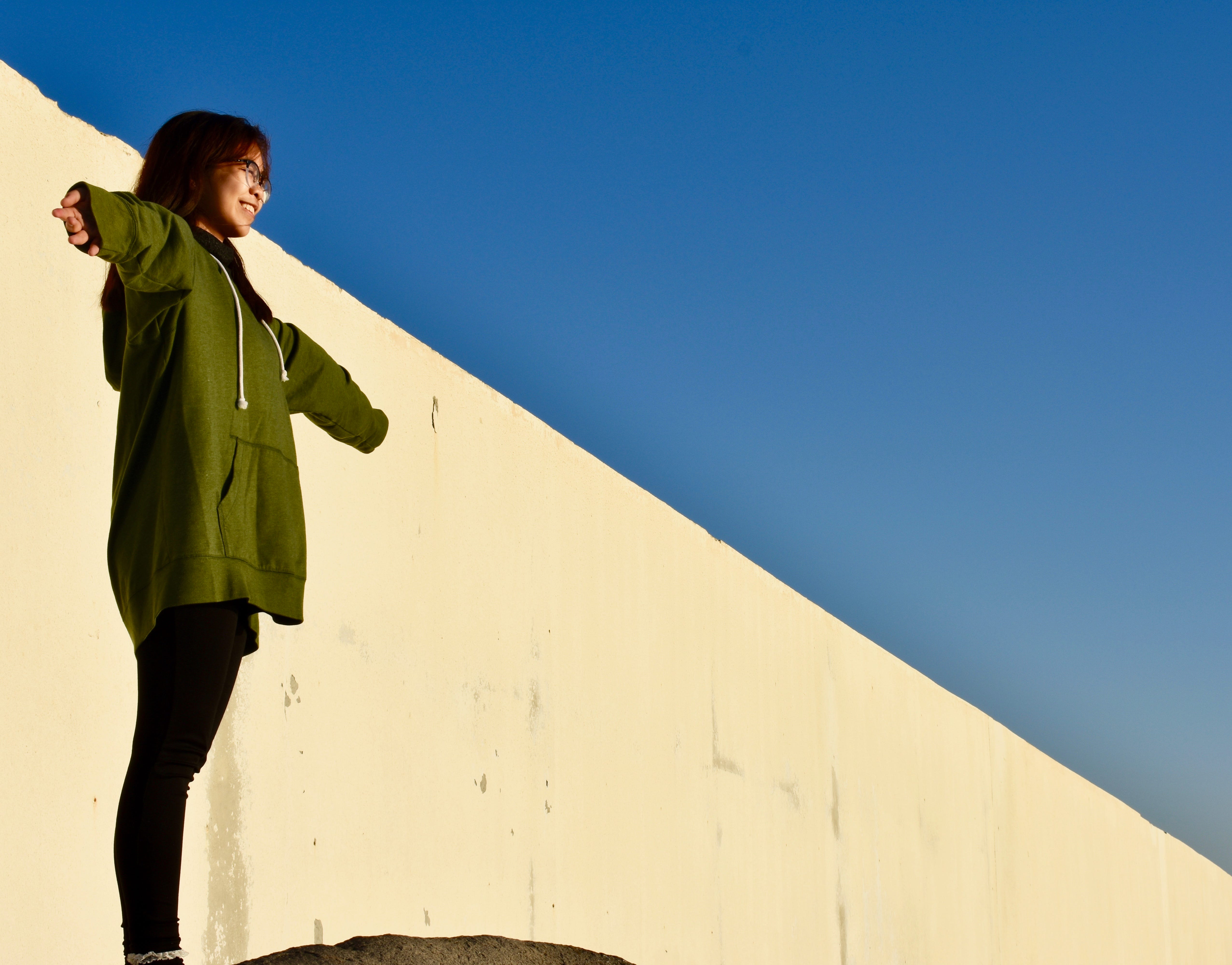 A teenager stretching her arms open wide in a clear blue sky